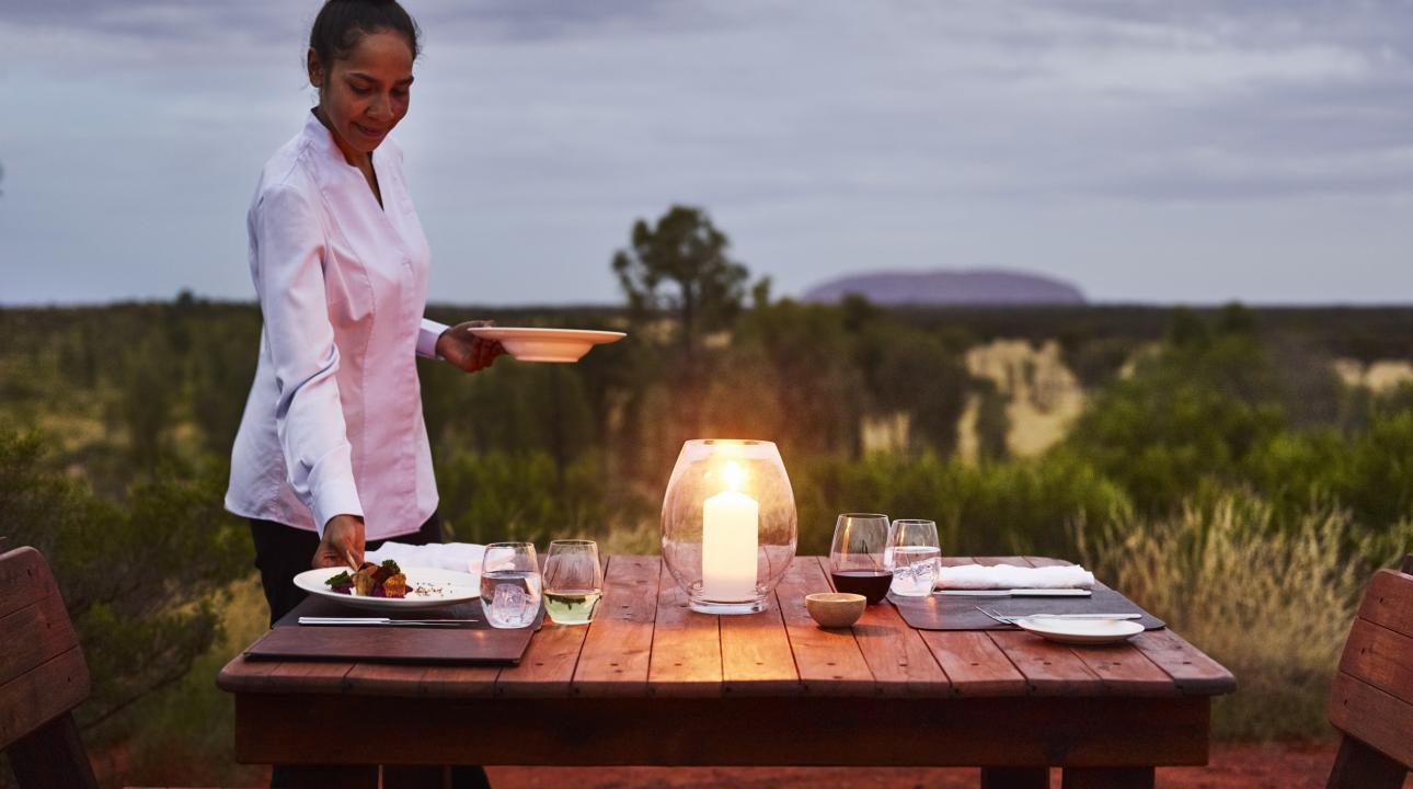 a waitress serving dinner at an outdoor table