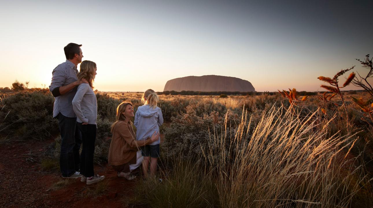 A family looking at Ayer's Rock at sunset