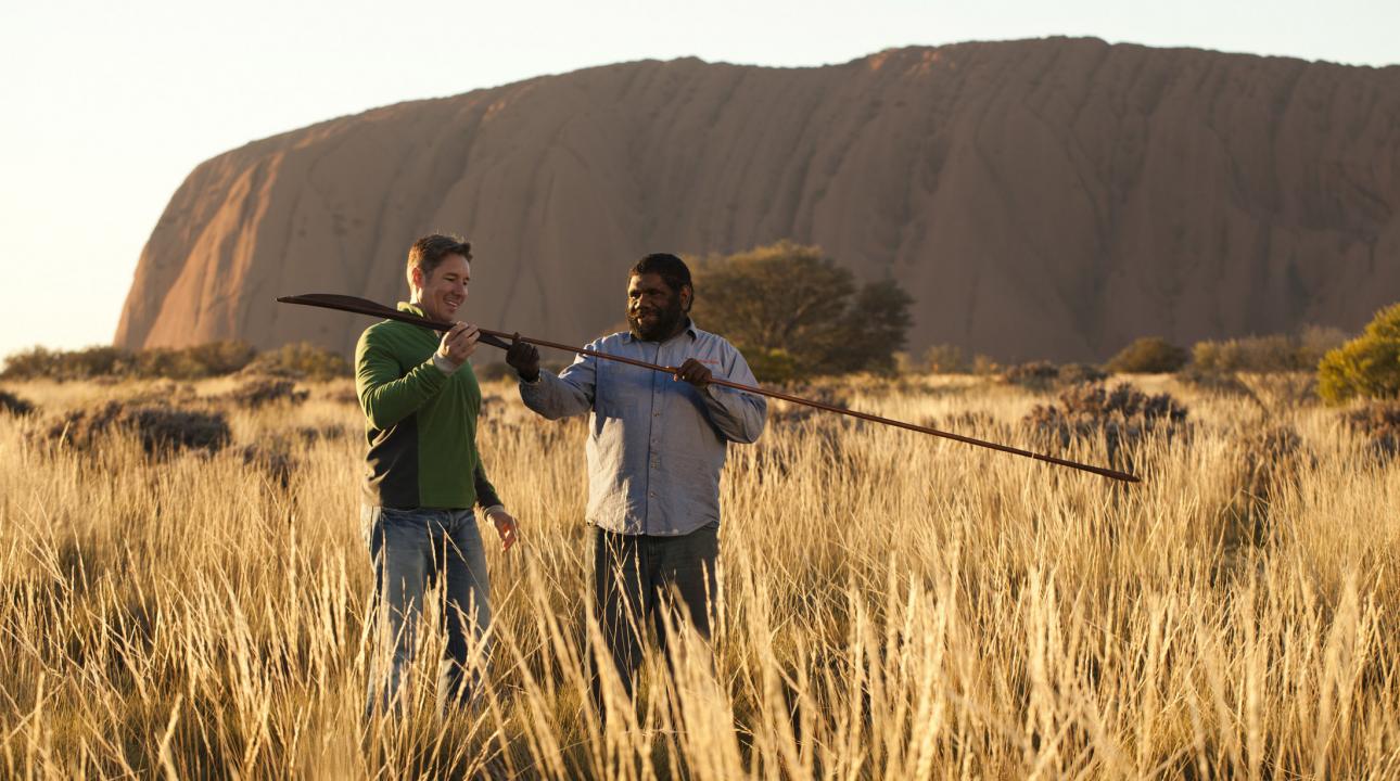 A man and a guide looking at a spear