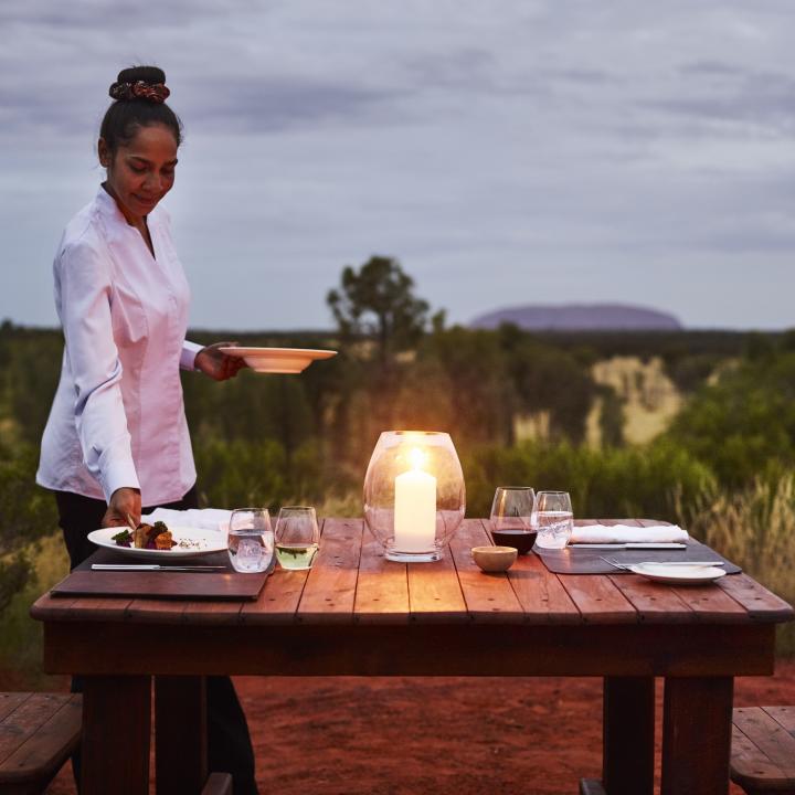 a waitress serving dinner at an outdoor table