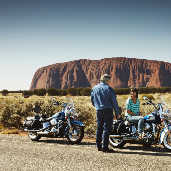 visitors on a Harley with uluru in the background