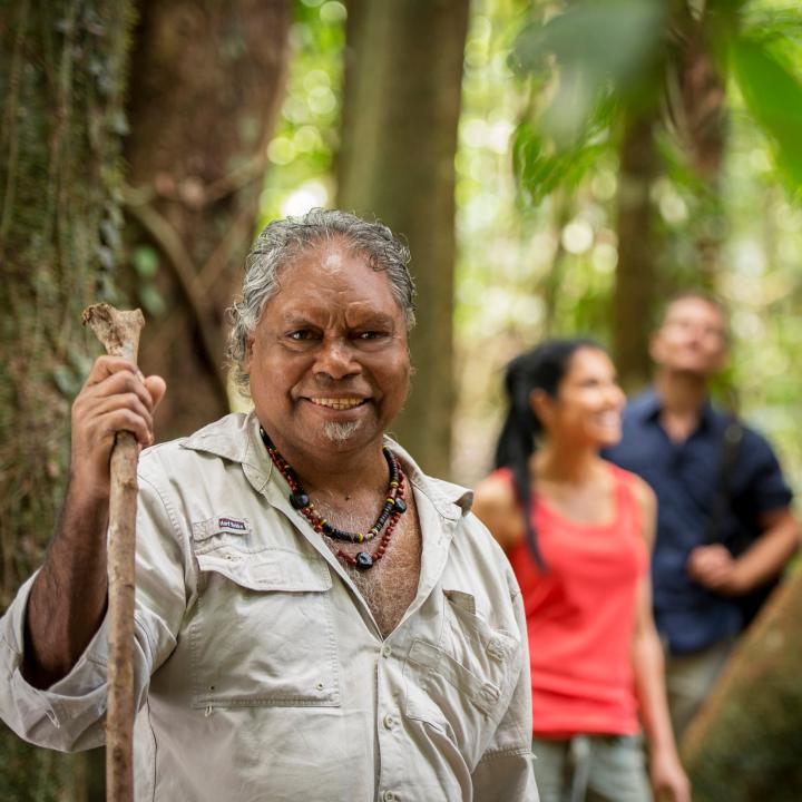 Guide with walking stick and tourists in the background