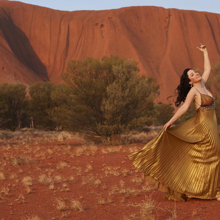 Woman dancing in a dress in front of Uluru