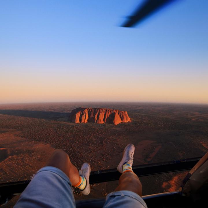 Man riding in a helicopter with his legs hanging out the side