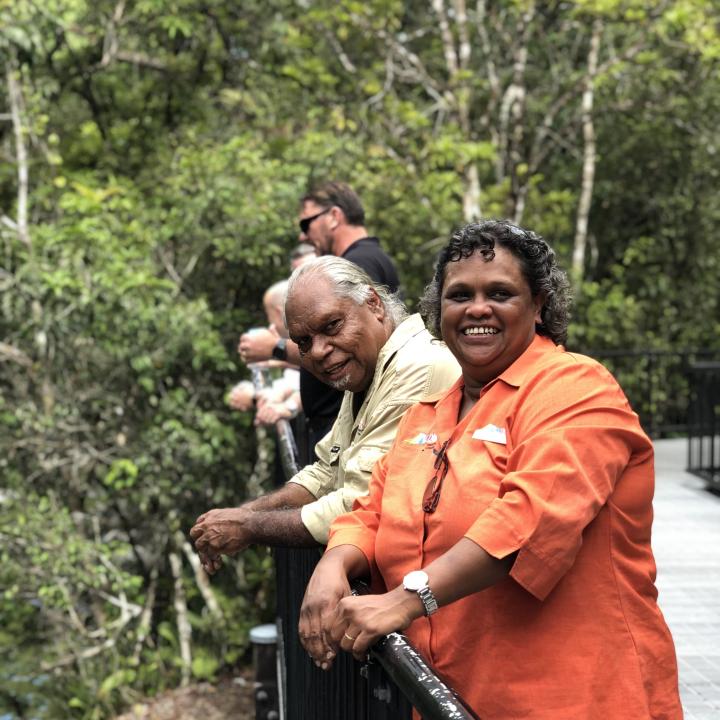Smiling staff pose against a rail with thick trees in the background