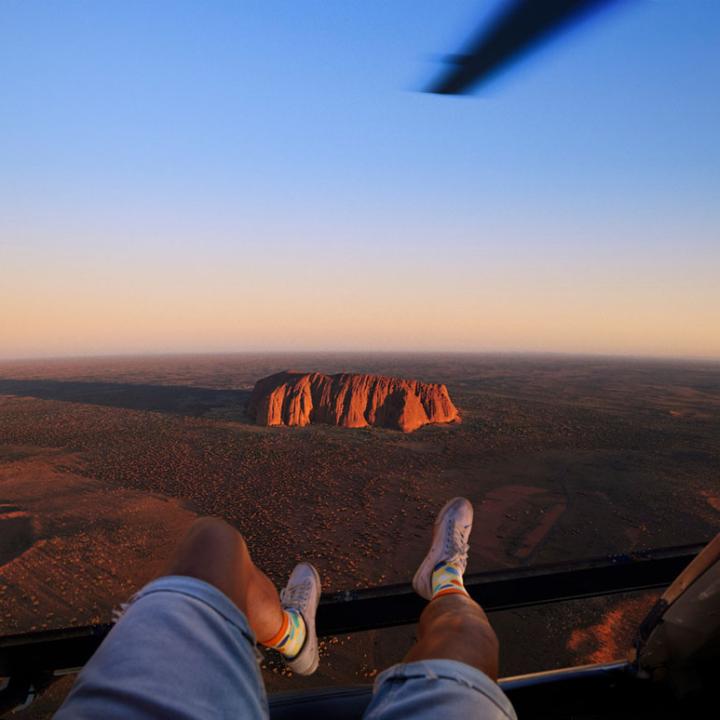 Man riding in a helicopter with his legs hanging out the side