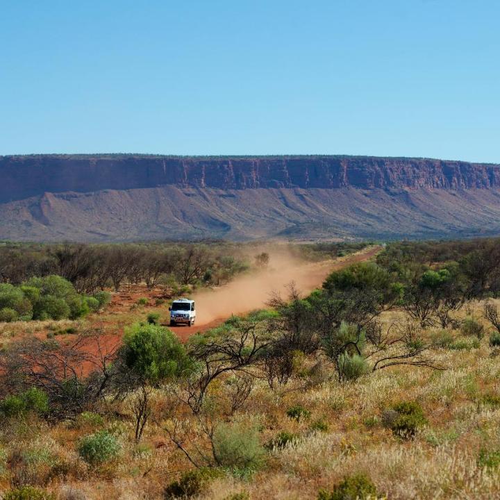 A car driving in front of Mt Conner in the Northern Territory