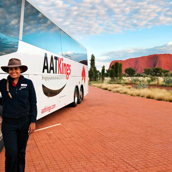 Driver guide standing next to AAT Kings coach in front of Uluru