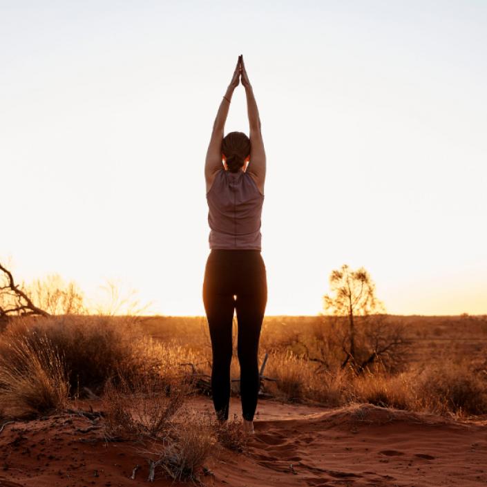 A woman performs yoga in the outback.