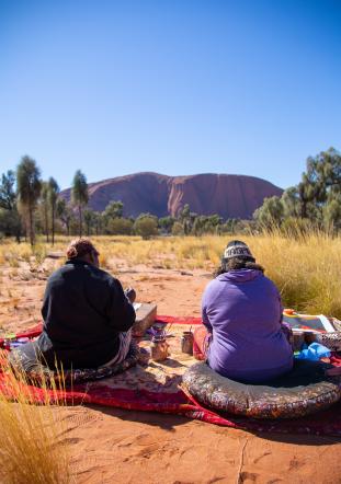 two people sitting on blankets in the outback